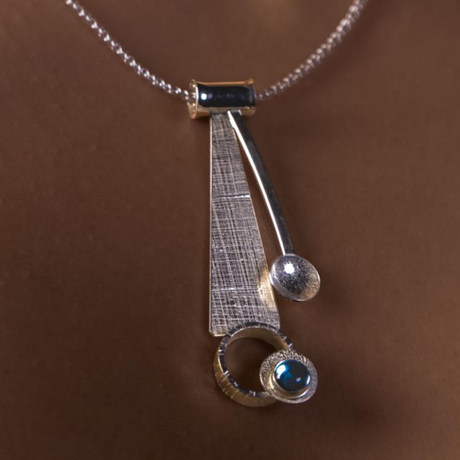 Model wearing a silver pendant with a blue stone