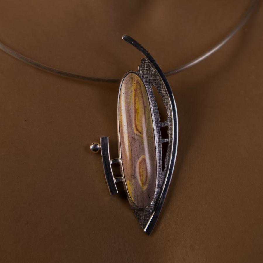 Model wearing a silver pendant with a long oval multi colored stone