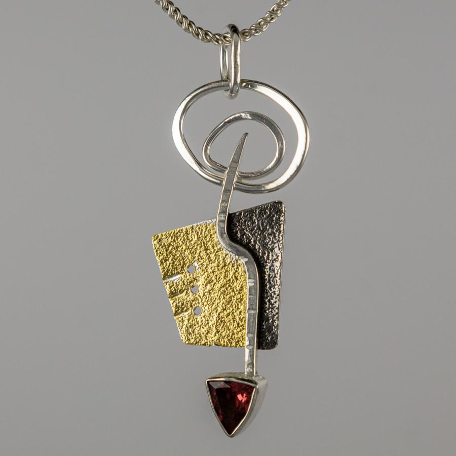 Silver and gold pendant with a red triangular stone