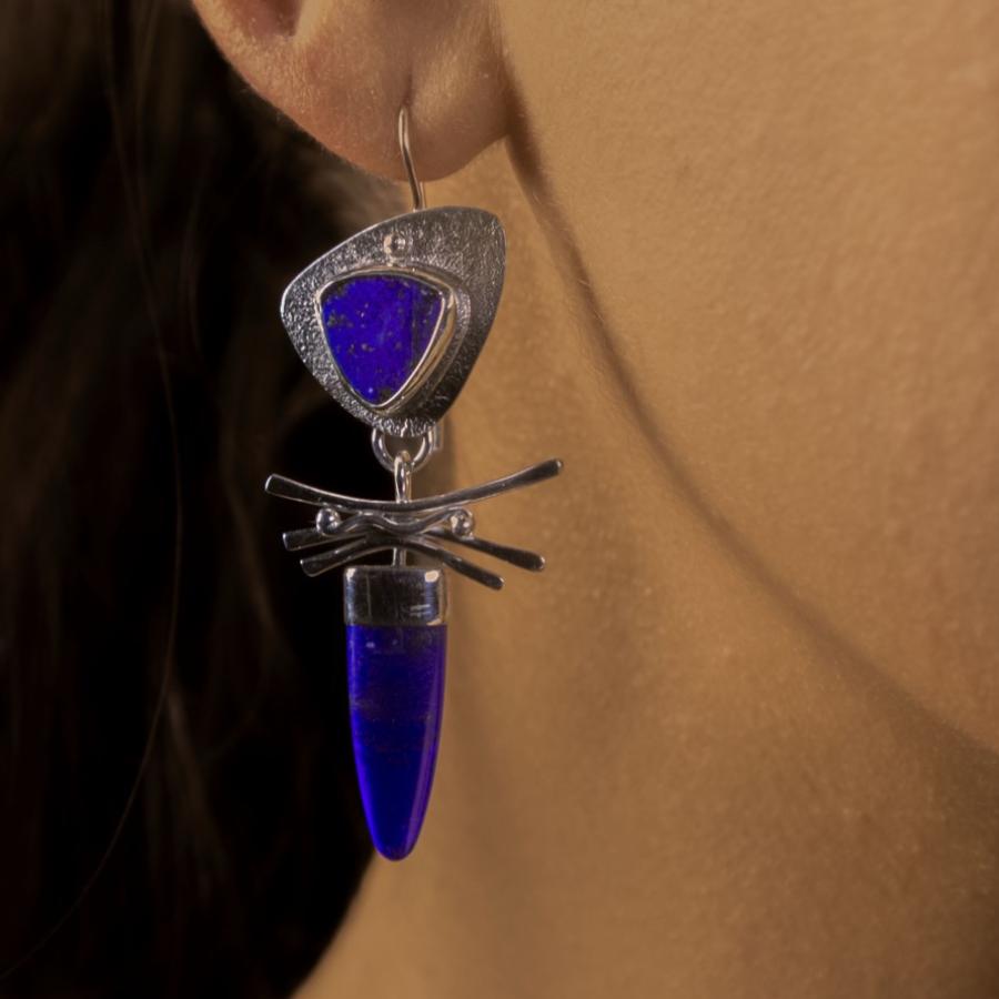Model wearing a silver earring with blue stones