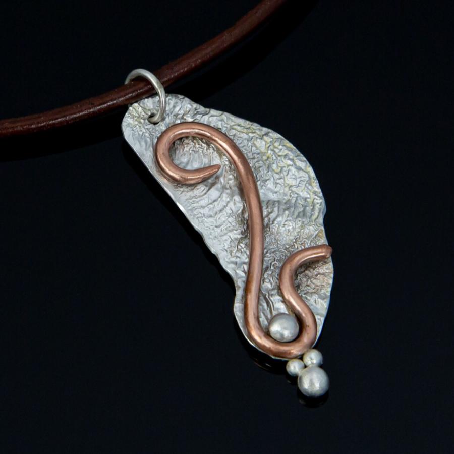 Silver and copper pendant on a brown leather cord