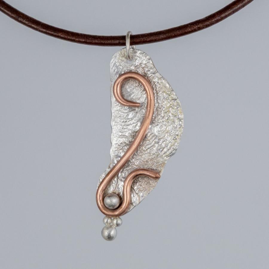 Silver and copper pendant on a brown leather cord
