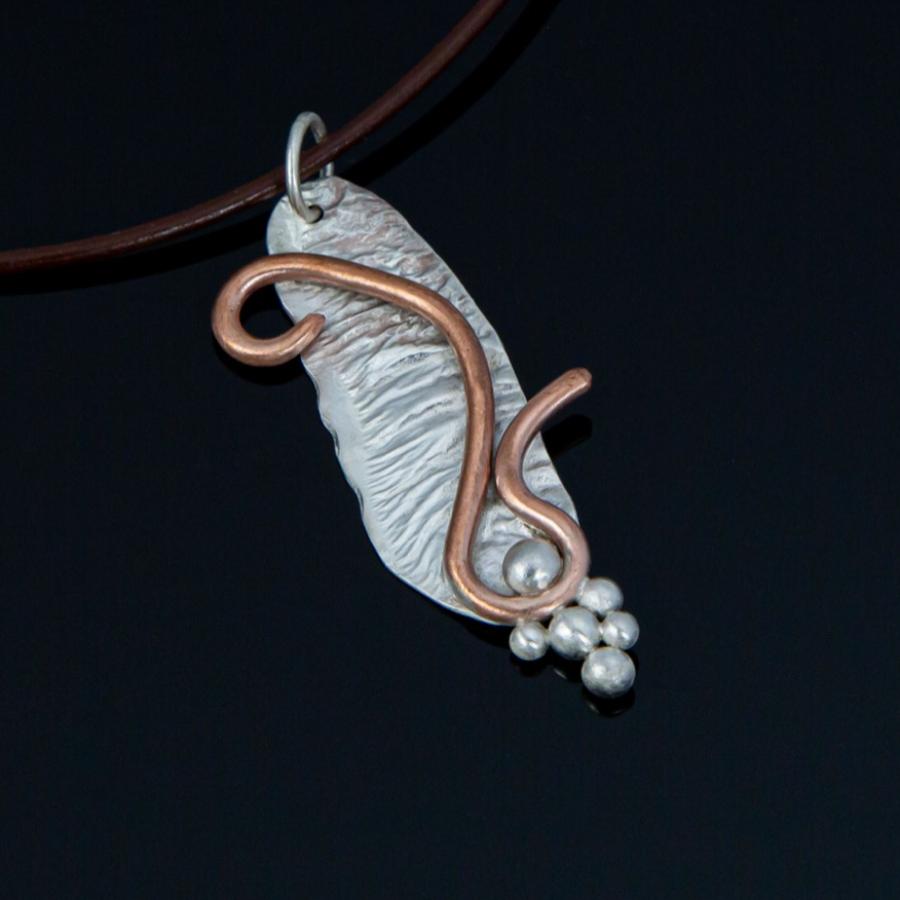 Silver and copper pendant on brown leather cord