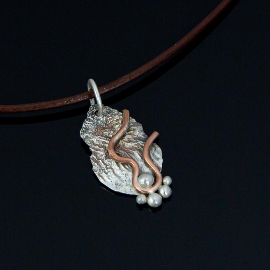 Silver and copper pendant on brown leather cord