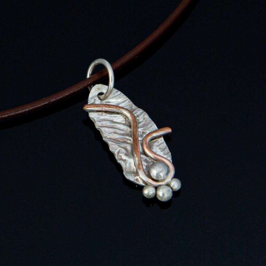 Silver and copper pendant on brown leather