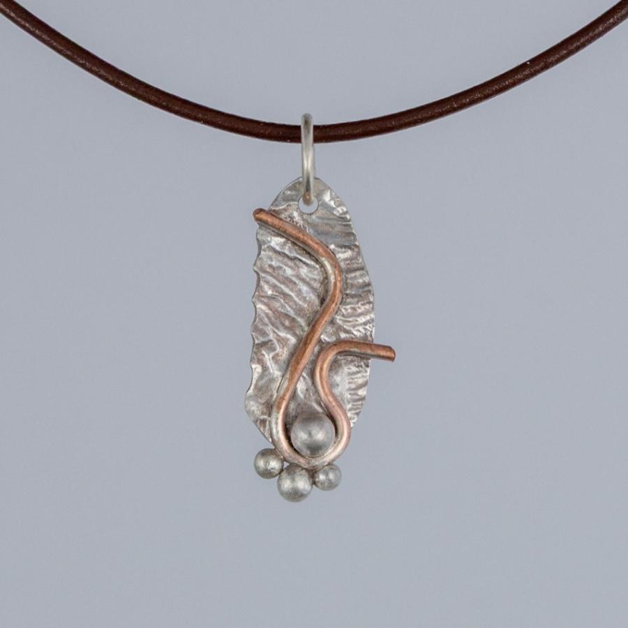 Silver and copper pendant on brown leather