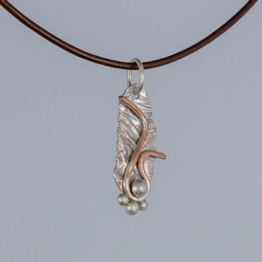 Silver and copper pendant on brown leather