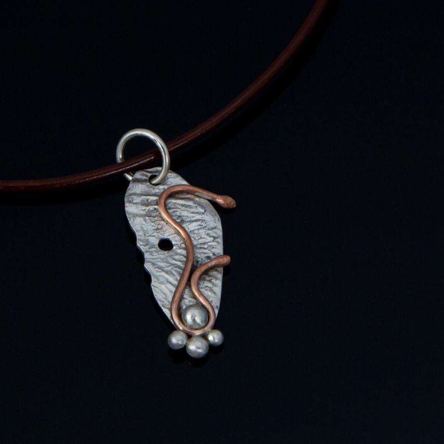 Silver and copper pendant on a brown cord