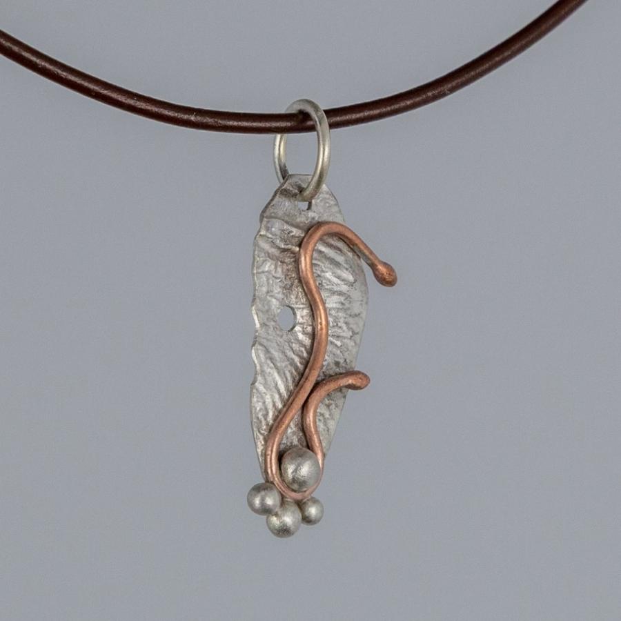 Silver and copper pendant on a brown cord