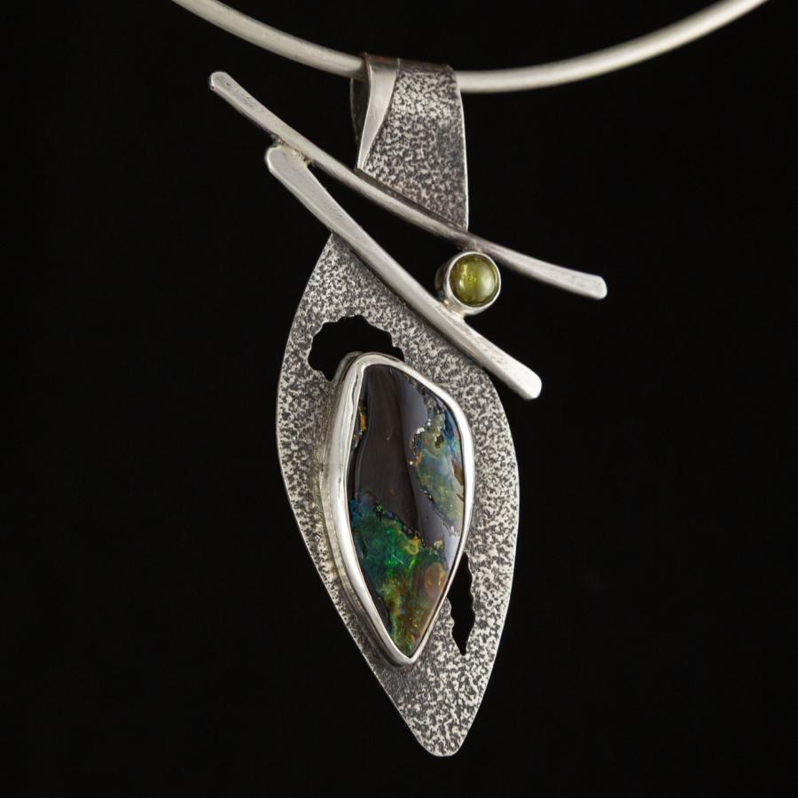 A silver pendant with green tinted stones