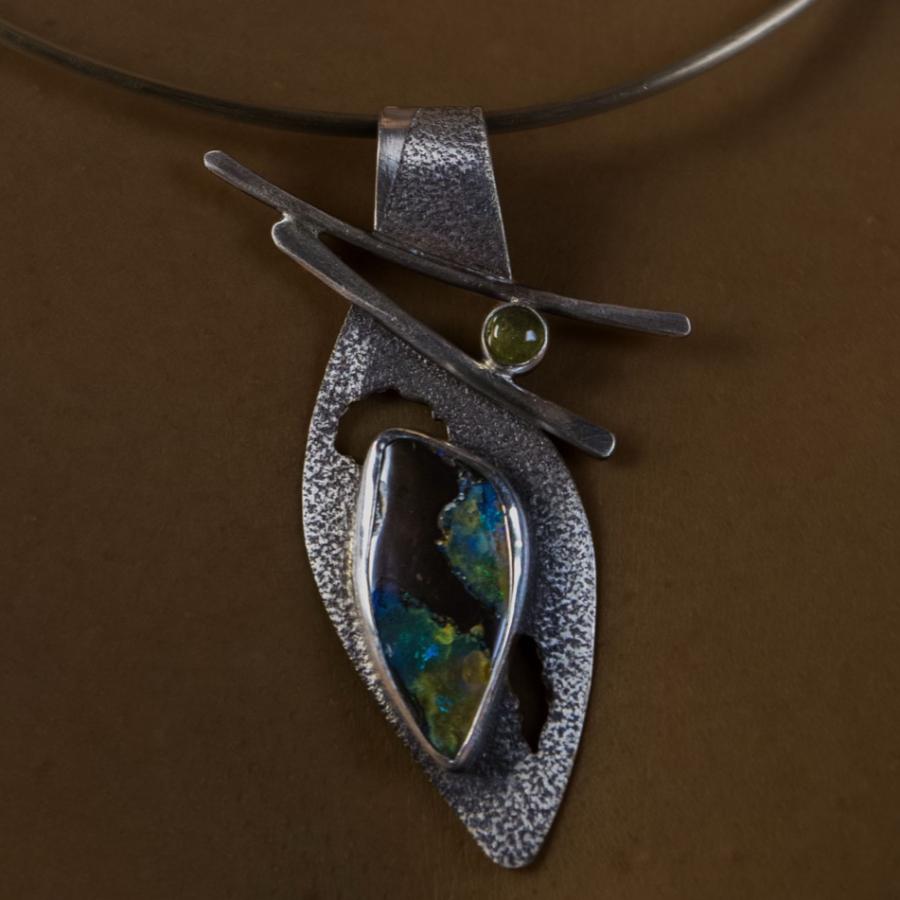 Model wearing a silver pendant with green tinted stones