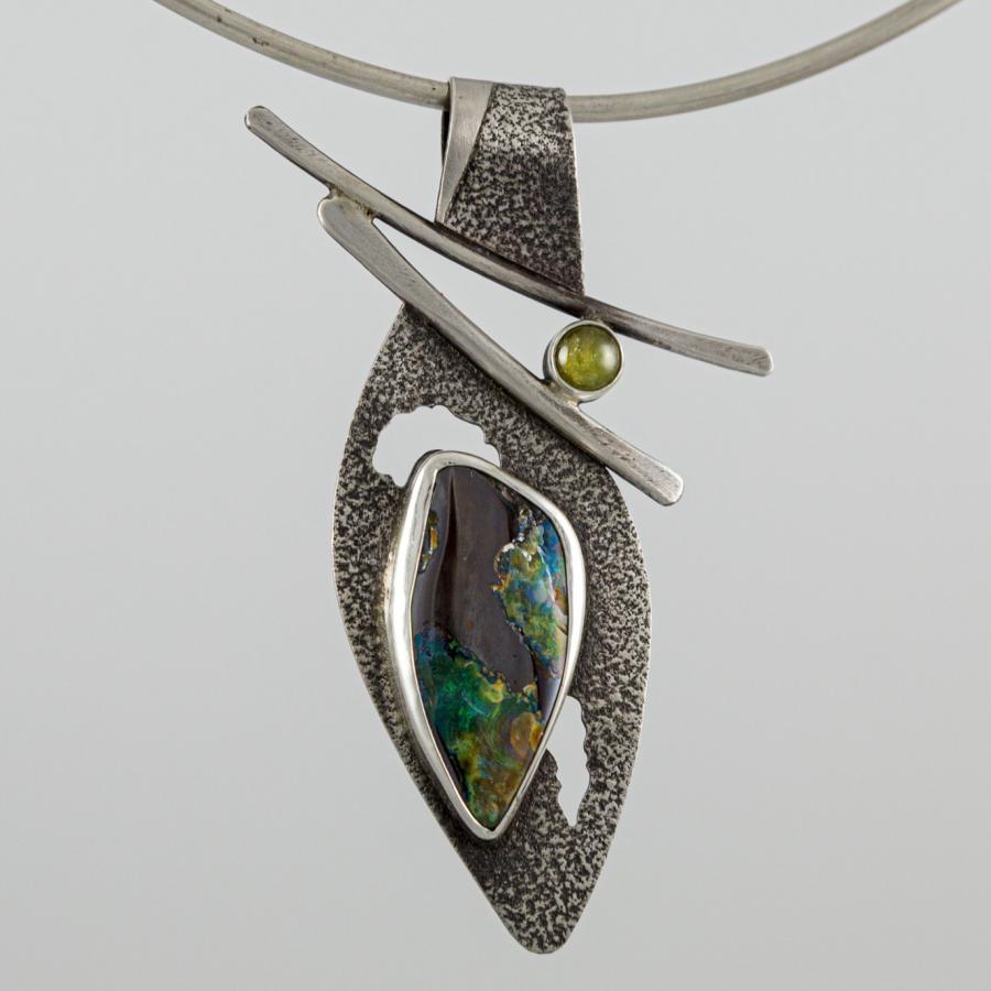 A silver pendant with green tinted stones