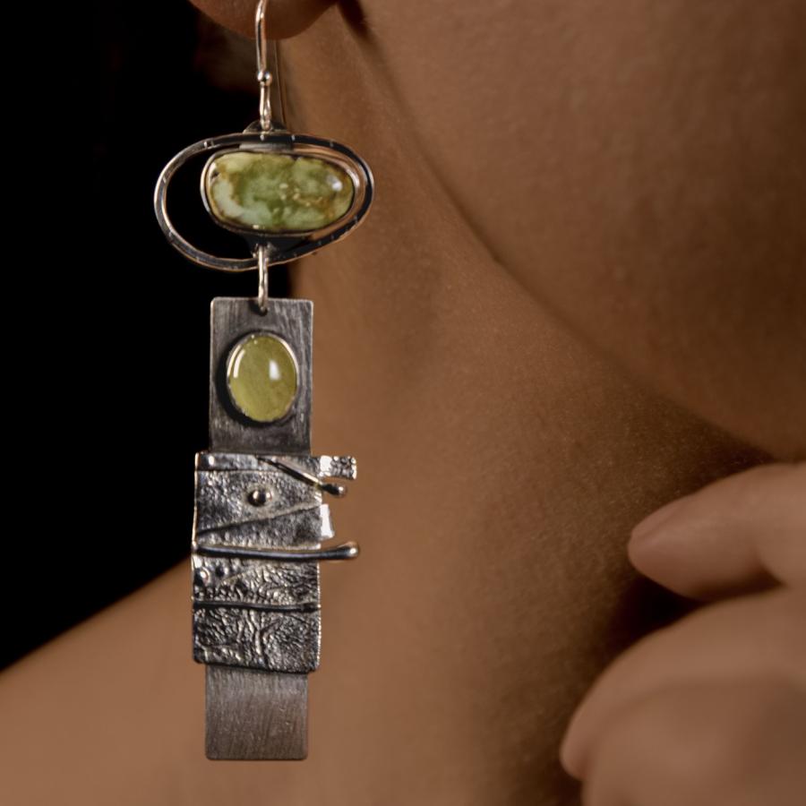 Model wearing a silver earring with green stones