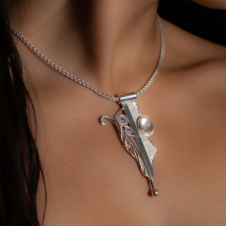 Model wearing a silver pendant with a pink stone