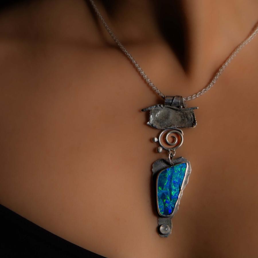 Model wearing a silver pendant with a dark blue opal