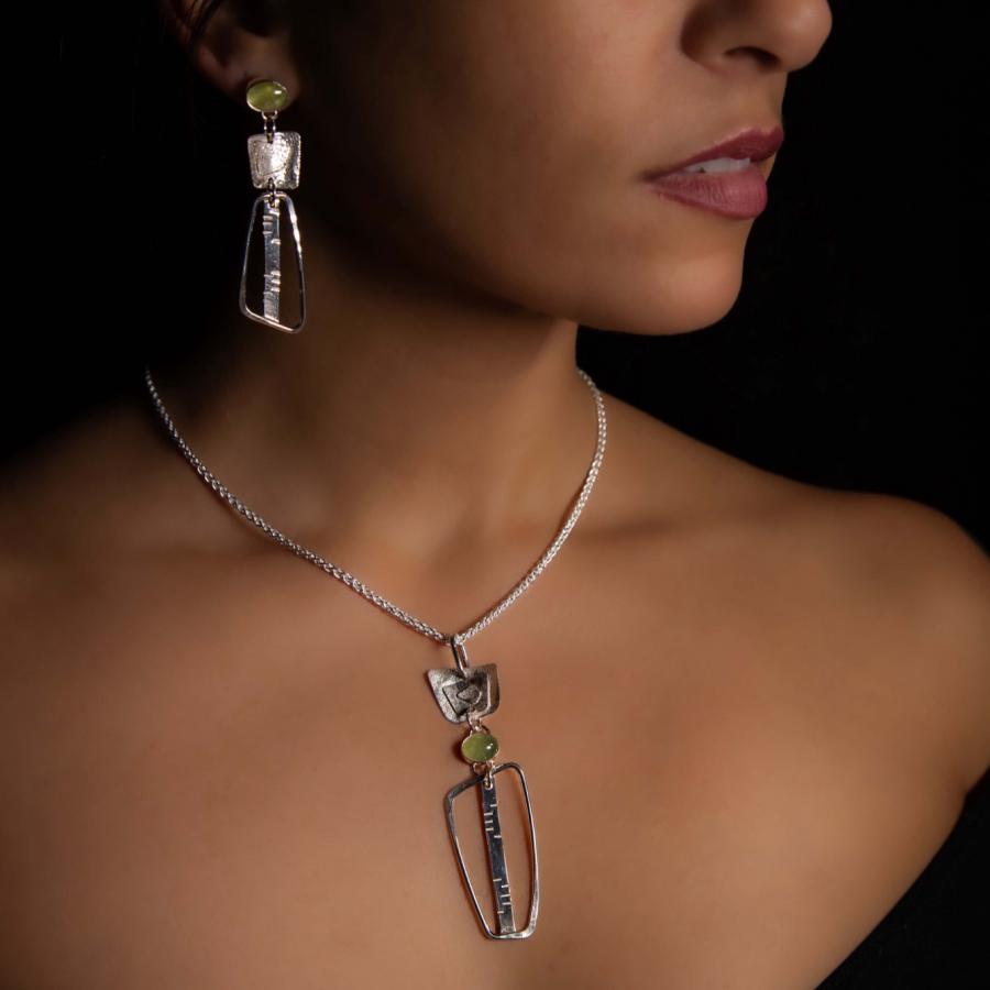 Model wearing a silver pendant and matching earrings