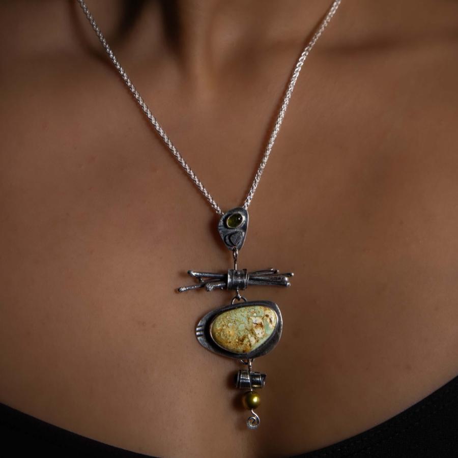 Model wearing a silver pendant with a green stone