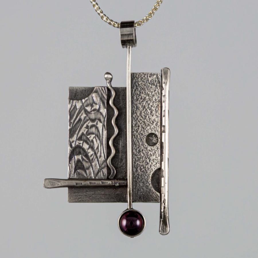 Geometric silver pendant with a red stone