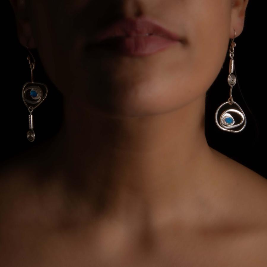 Model wearing silver earrings with blue/green stones