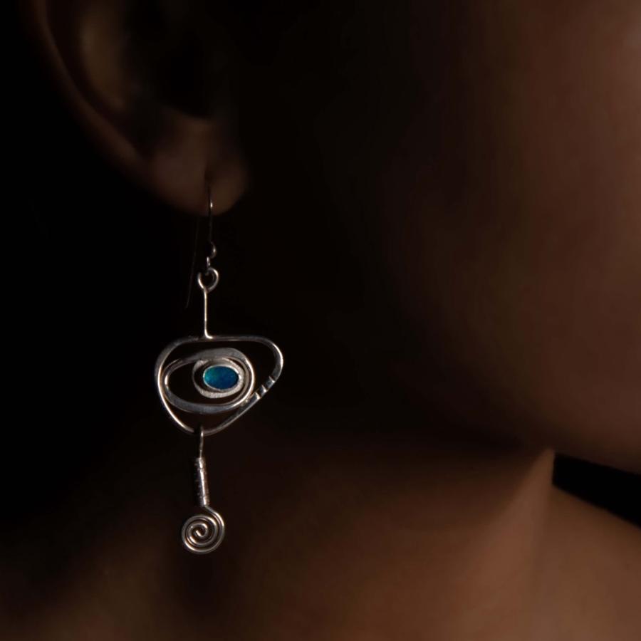 Model wearing a silver earring with blue/green stones