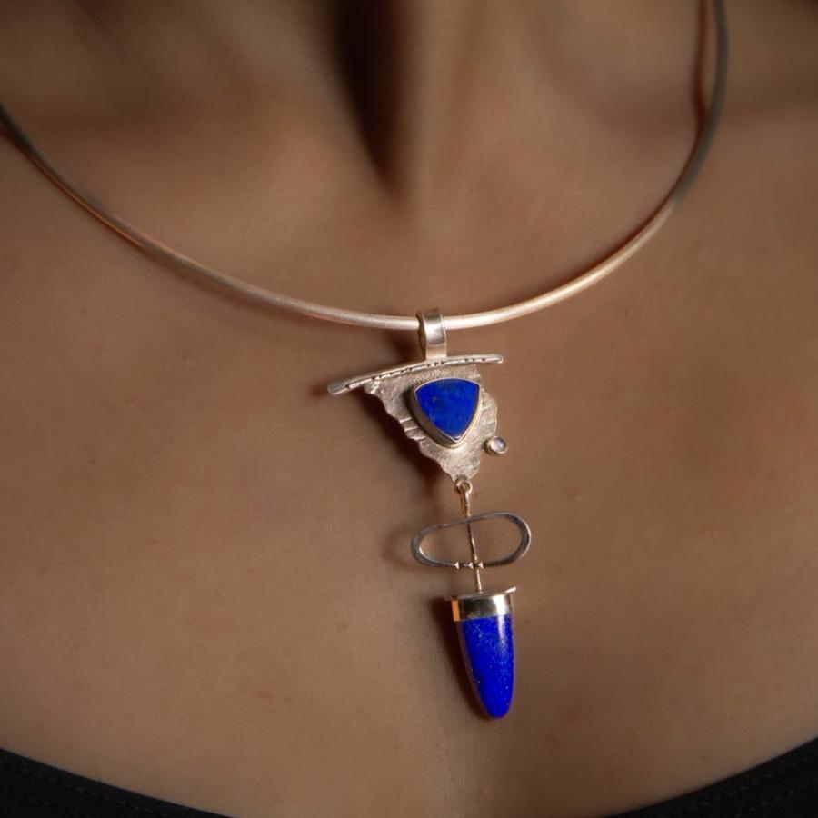 Model wearing a silver pendant with blue stones