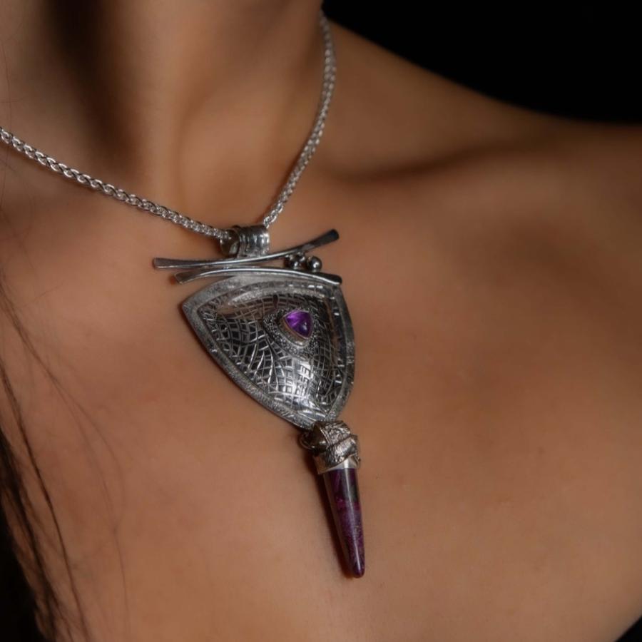 Model wearing a trillion shaped pendant with a dangling purple stone.