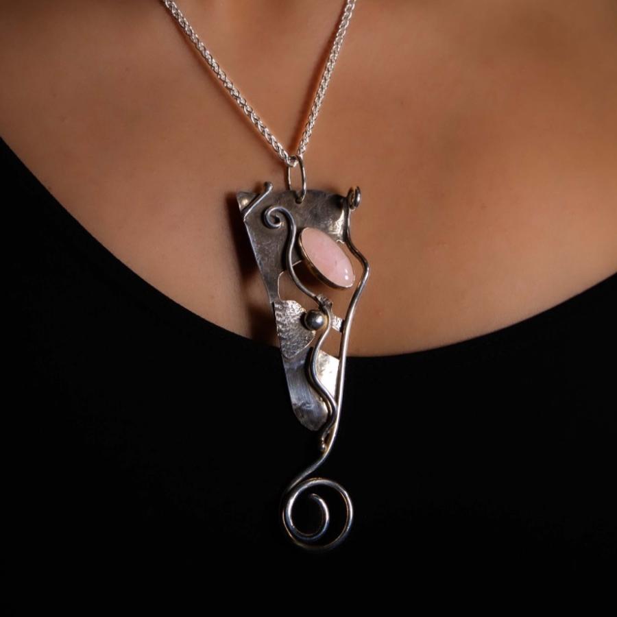Model wearing a silver pendant with a pink stone