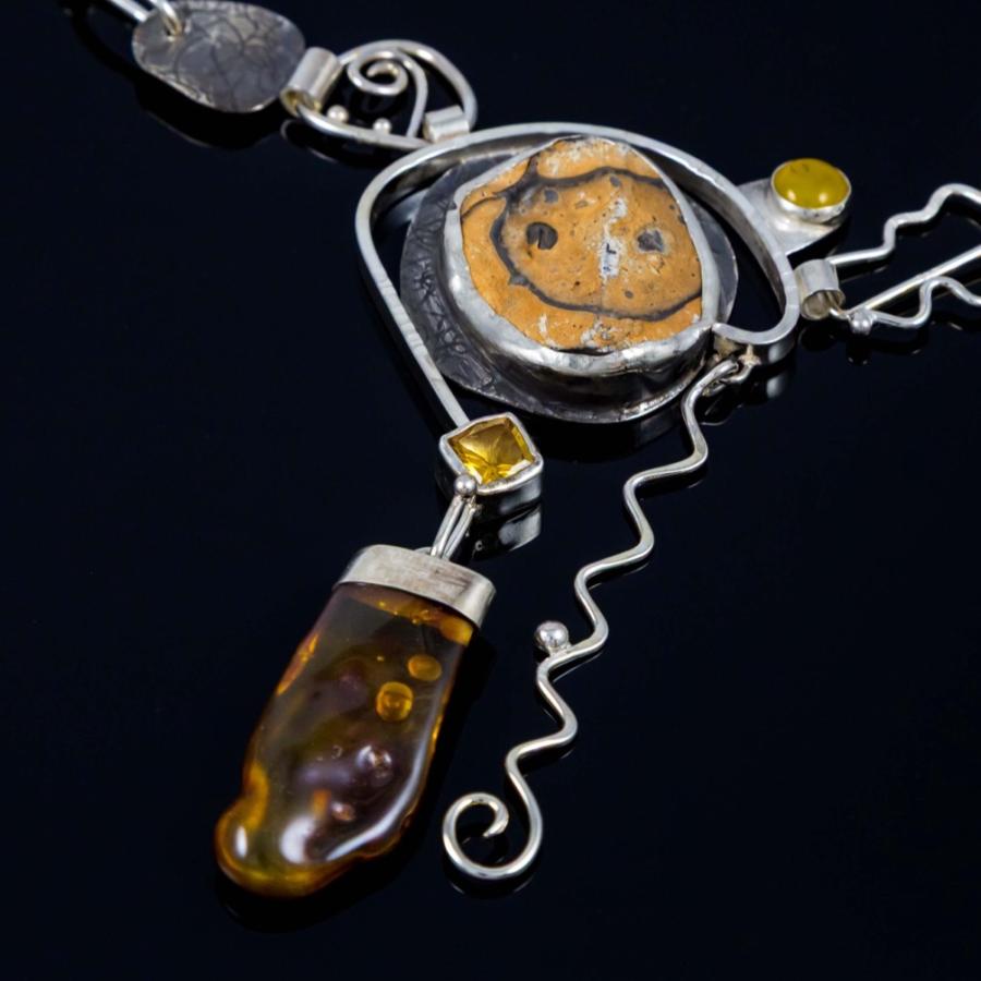 Silver pendant with yellow stones. One looks like a smiling face.