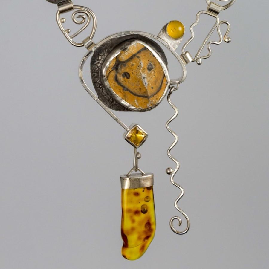 Silver pendant with yellow stones. One looks like a smiling face.