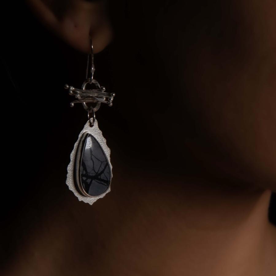 Model wearing silver earrings with black stones