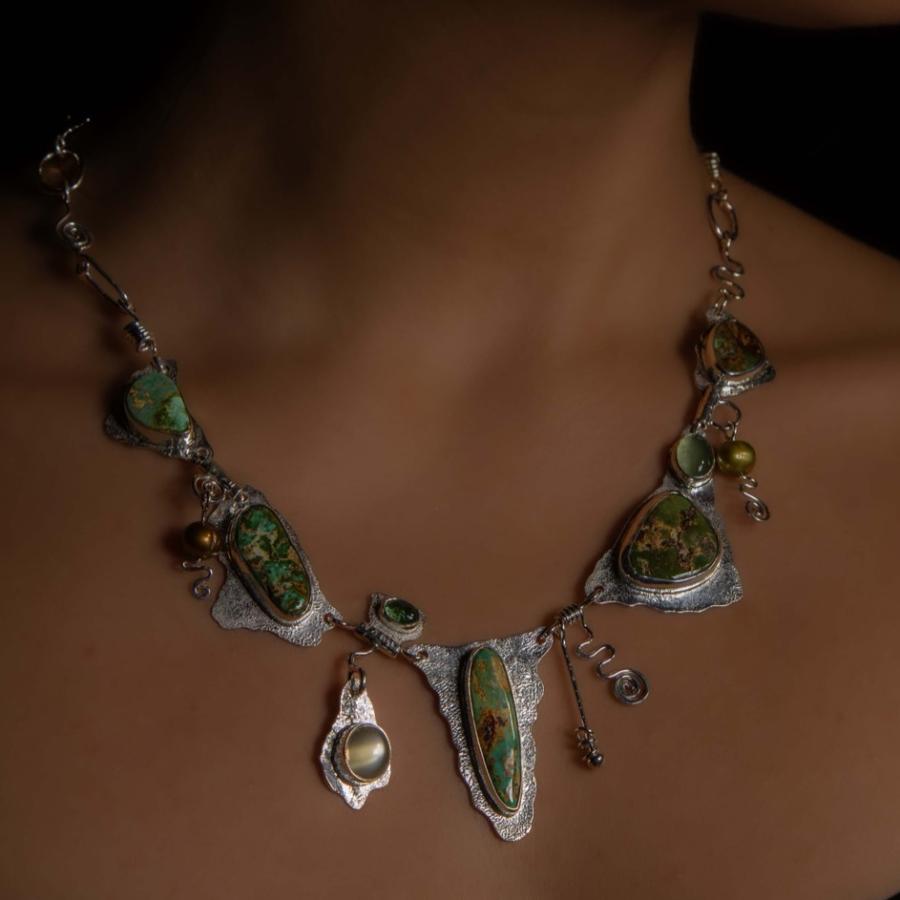 Model wearing a silver necklace with multiple green stones