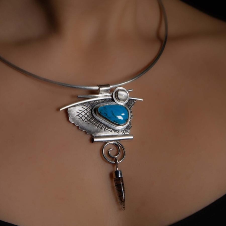 Model wearing a silver pendant with a blue stone