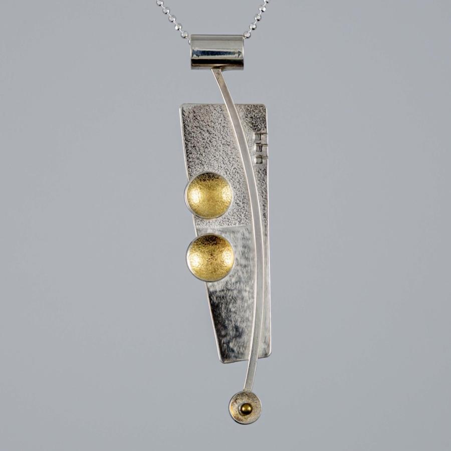 A silver pendant with gold accents