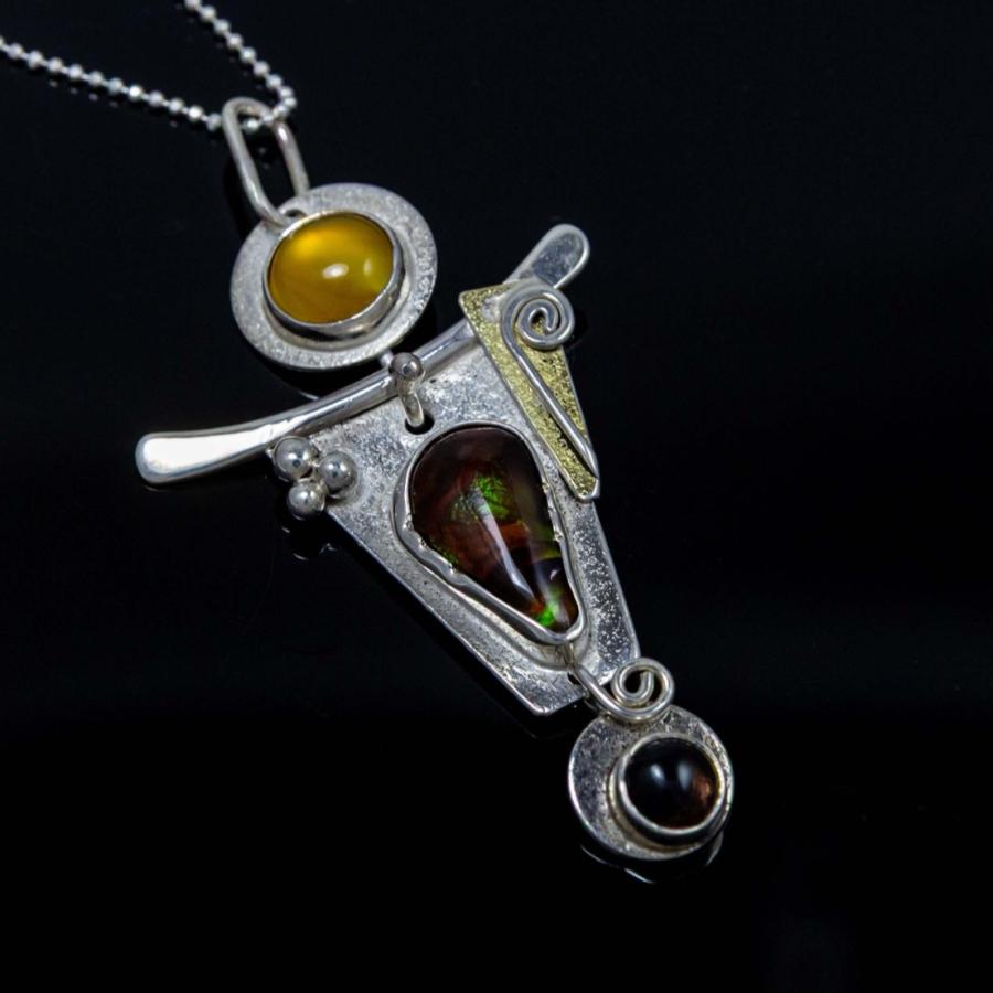 Abstract silver pendant necklace with amber and opal stones against a black background.