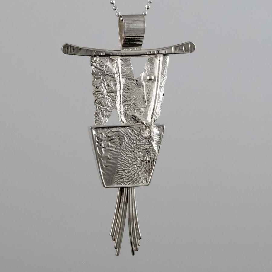 Photograph of a textured silver pendant on a delicate chain against a gray background.