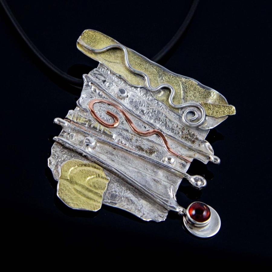 Abstract mixed-metal pendant with silver, gold accents, and a small red gemstone on a black cord.
