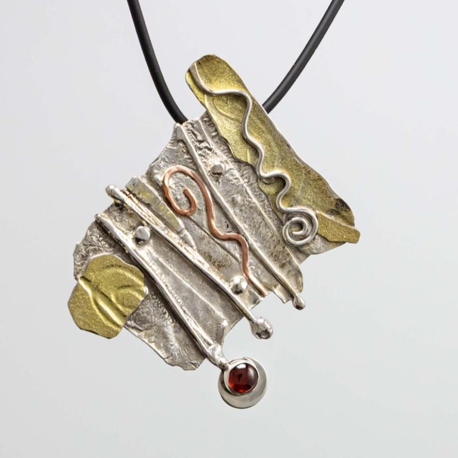 Abstract mixed-metal pendant with silver, gold accents, and a small red gemstone on a black cord.