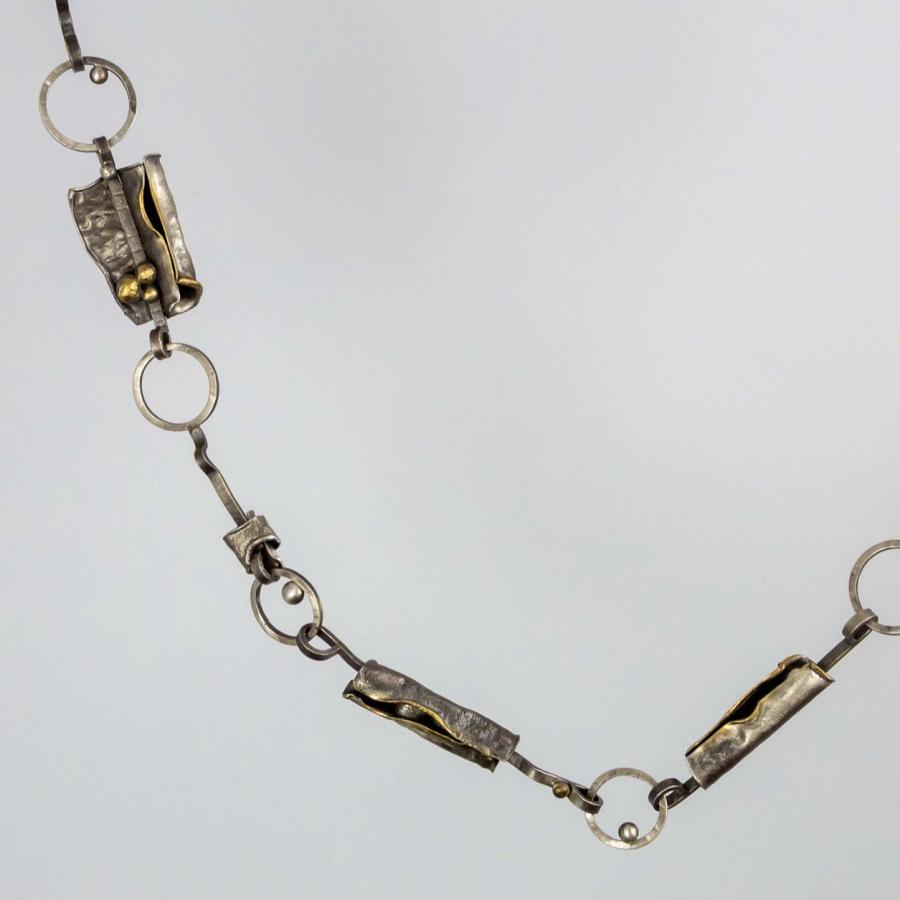 Photograph of a necklace with textured silver and gold links connected by rings.