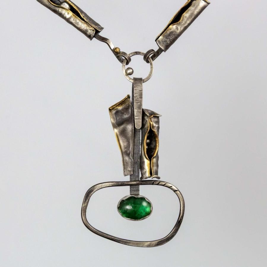 Abstract silver necklace with a green gemstone pendant.