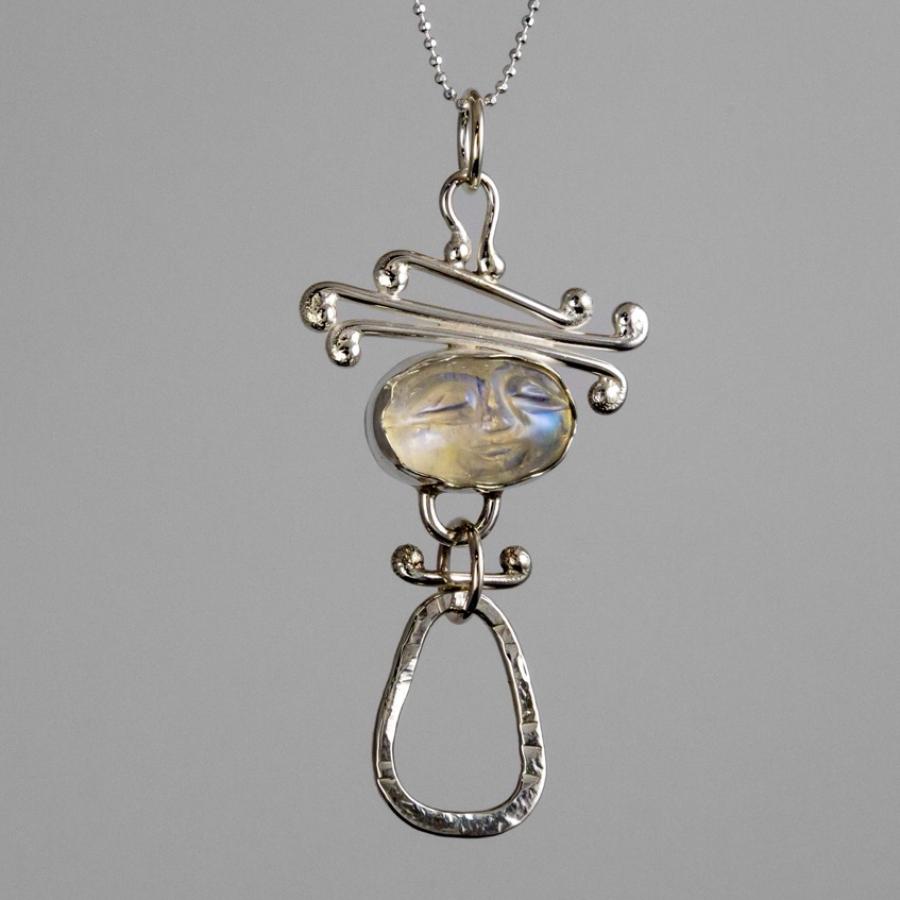 Photograph of a silver pendant featuring an oval stone and an organic, open-loop design.