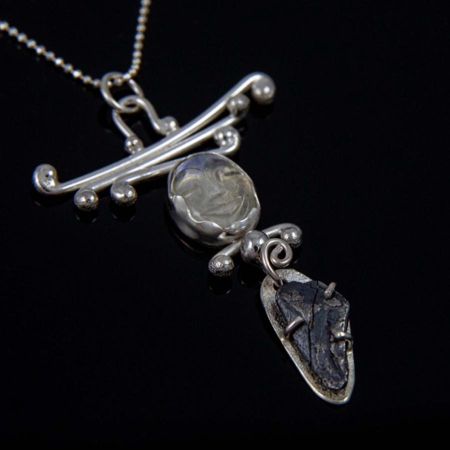 Photograph of a silver pendant necklace with two stones on a black background.
