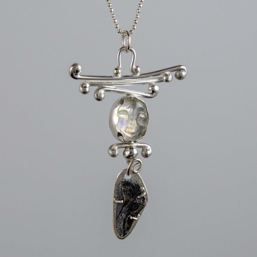 Silver pendant necklace featuring a round moonstone and a dark, organic stone drop.