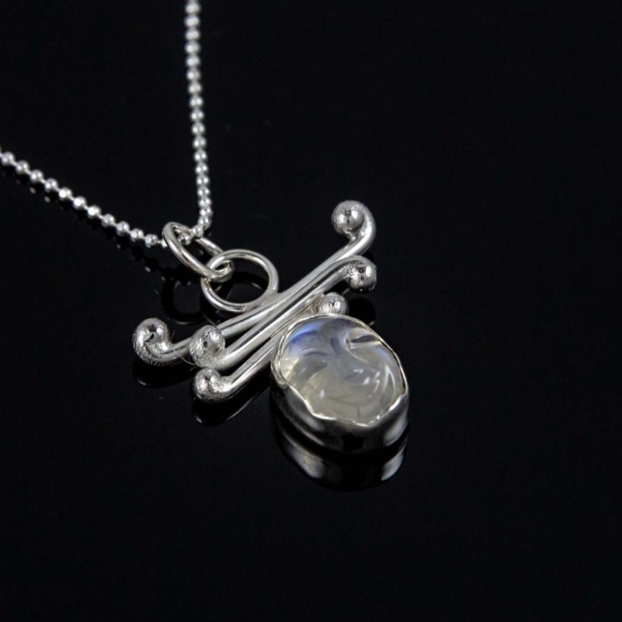 A silver necklace with an oval moonstone pendant on a black background.