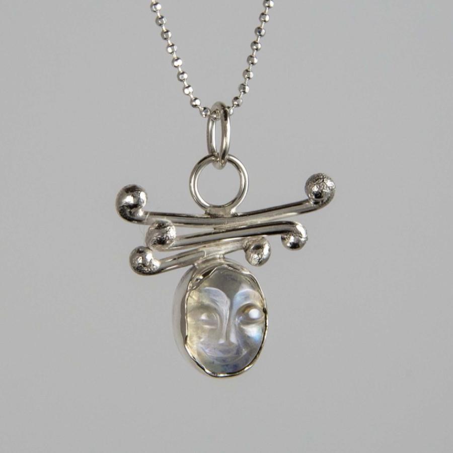 Silver necklace with an oval stone pendant featuring decorative, curling metalwork.