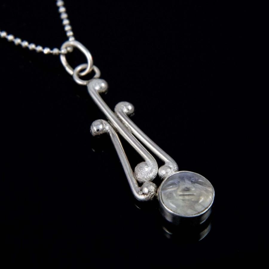 Silver necklace with an art deco style pendant featuring a round iridescent stone.
