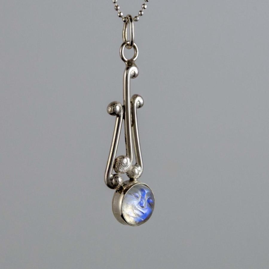 Silver pendant necklace with a small iridescent moonstone against a neutral grey background.
