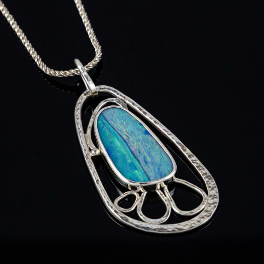 Silver pendant necklace featuring a blue opal set in an ornate, openwork frame against black.