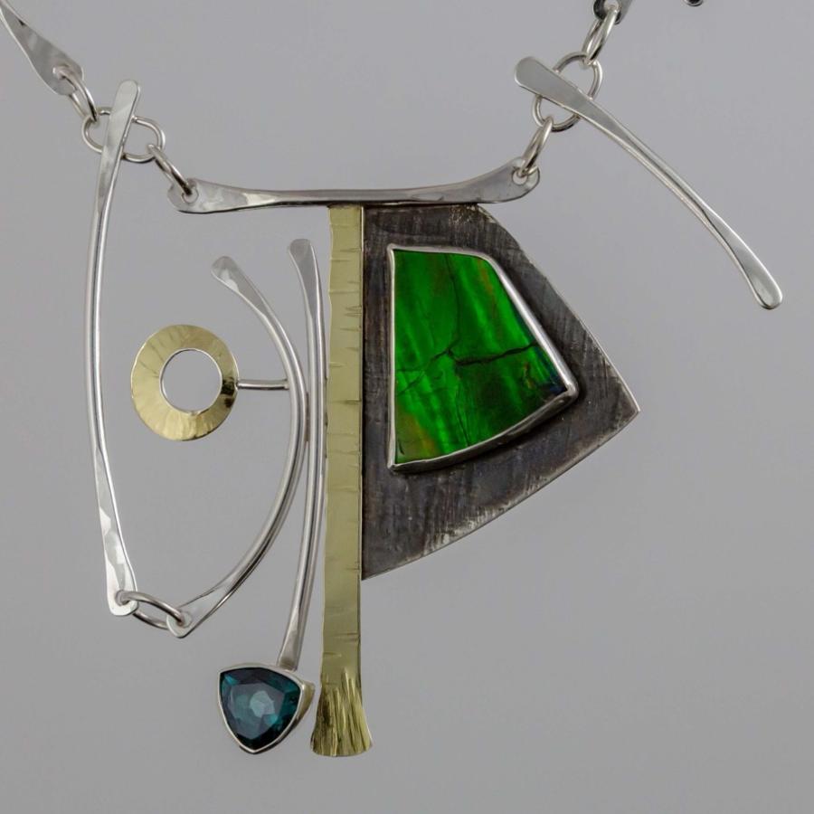 Modern silver necklace with an abstract pendant featuring a green ammolite and a small blue stone.