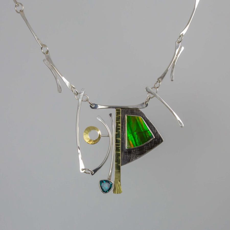 Modern silver necklace with an abstract pendant featuring a green ammolite and a small blue stone.