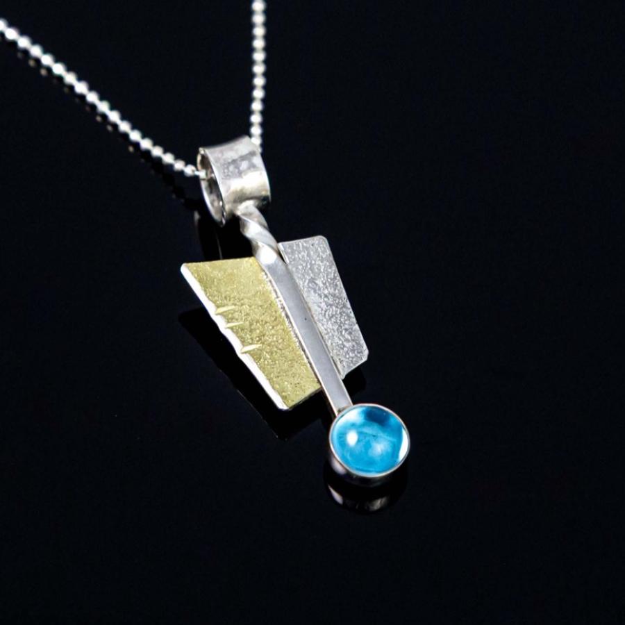 A geometric silver and gold pendant necklace with a blue stone on a black background.